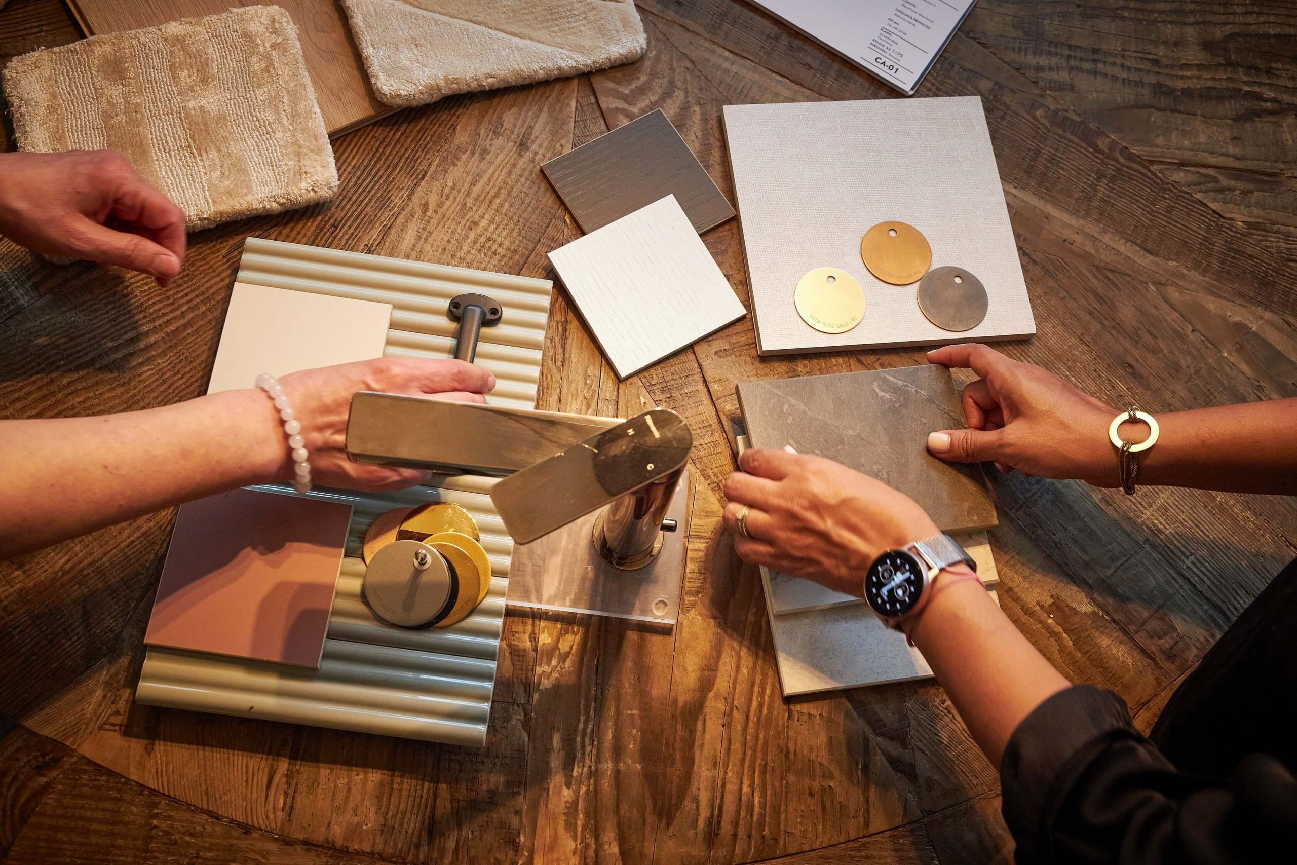 Selección de materiales y muestras sobre mesa durante la planificación de obra.
