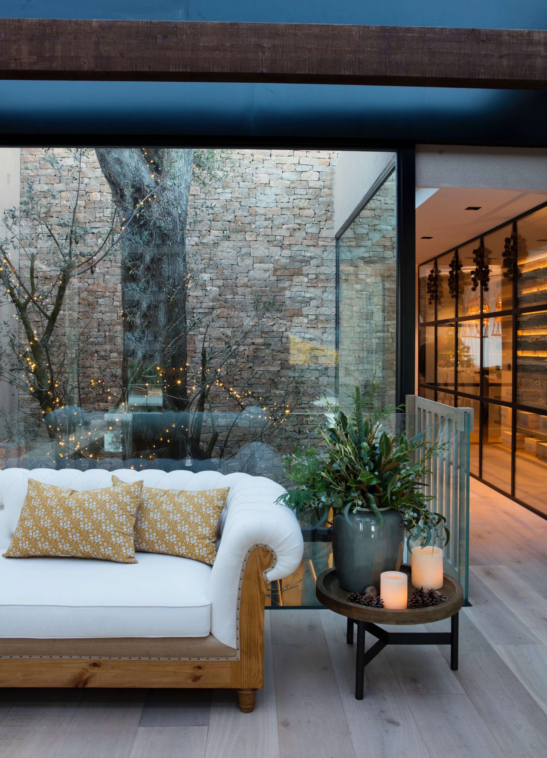 Salón acristalado con sofá y patio ajardinado en vivienda de Barcelona.