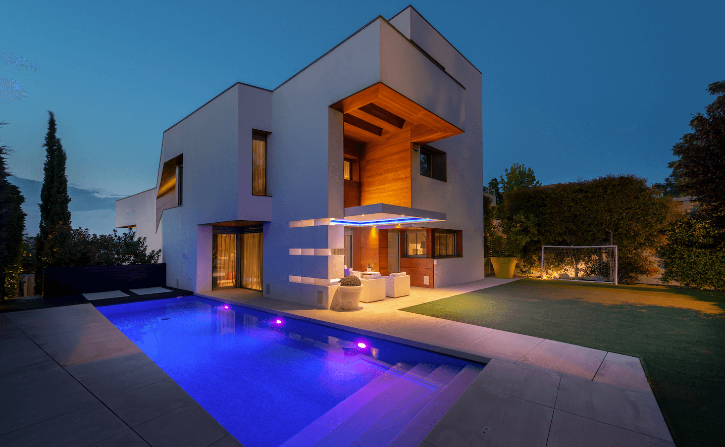 Vivienda moderna con piscina iluminada al atardecer.