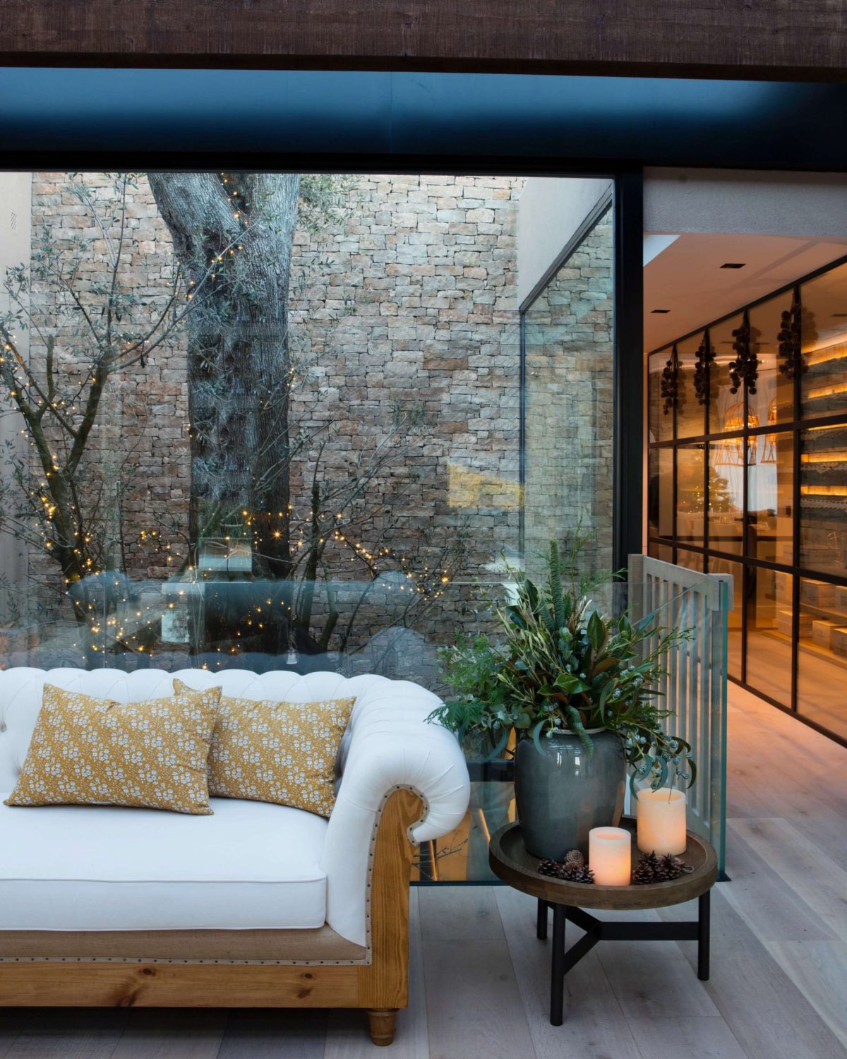 Salón acristalado con sofá y patio ajardinado en vivienda de Barcelona.